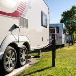 E-Wohnwagen lädt an einer Steckdose auf einem Campingplatz
