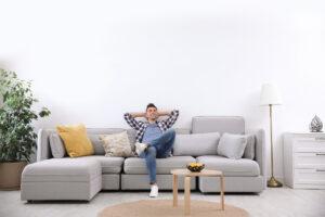 Junger Mann, der sich zu Hause auf dem Sofa, bei angenehmen Raumklima entspannt